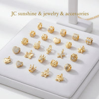Collection of gold-tone charms and beads for bracelets, featuring hearts, stars, flowers, animals, and letters.